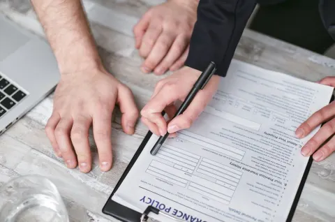 Deux personnes qui signent un contrat d'assurance sur un bureau en bois