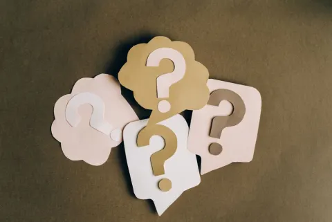 Points d'interrogation en papier découpé sur fond brun
