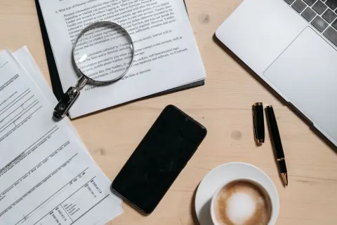 Bureau avec documents, ordinateur portable, café et loupe