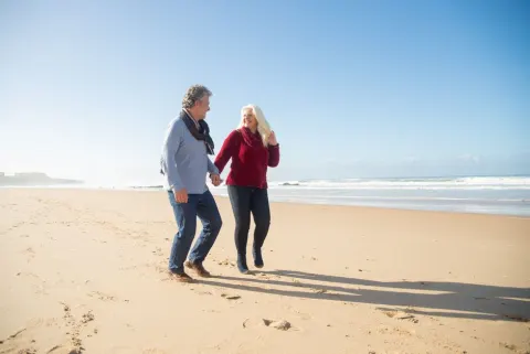 Couple de seniors qui se tient la main sur une plage